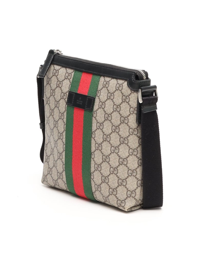 Side view of a Gucci Messenger Bag in beige GG Supreme canvas with its signature green and red Web stripe and black strap.