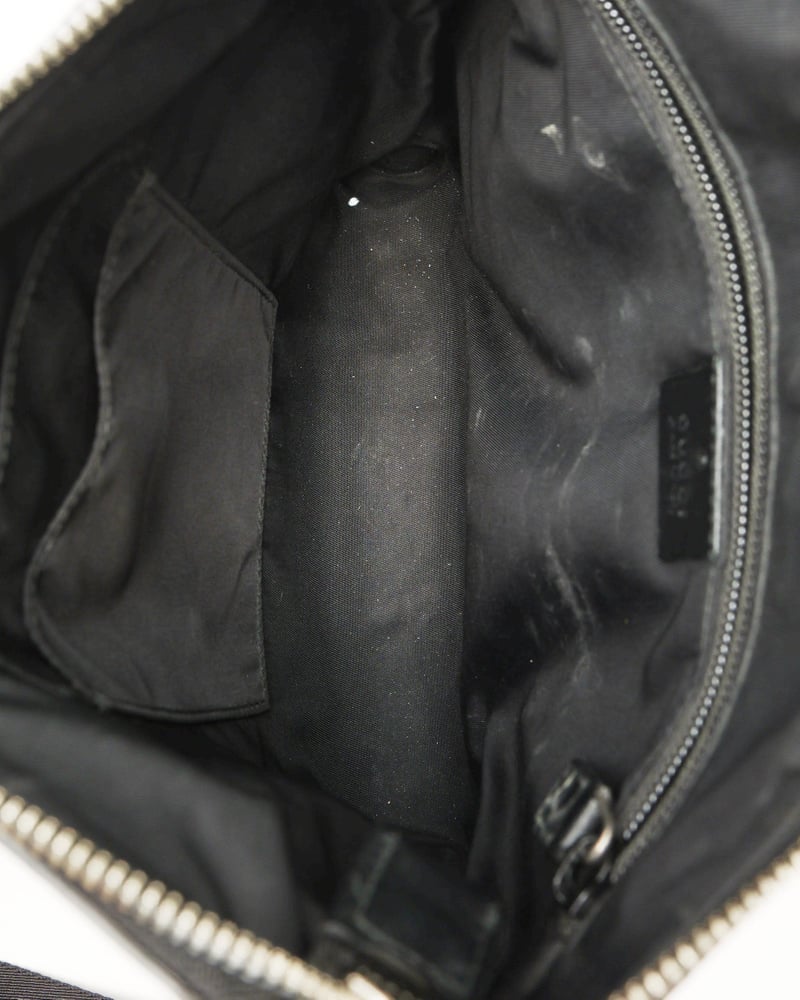 Inside view of a vintage Gucci Messenger Bag, showing its black fabric lining, internal pockets, and visible signs of wear.