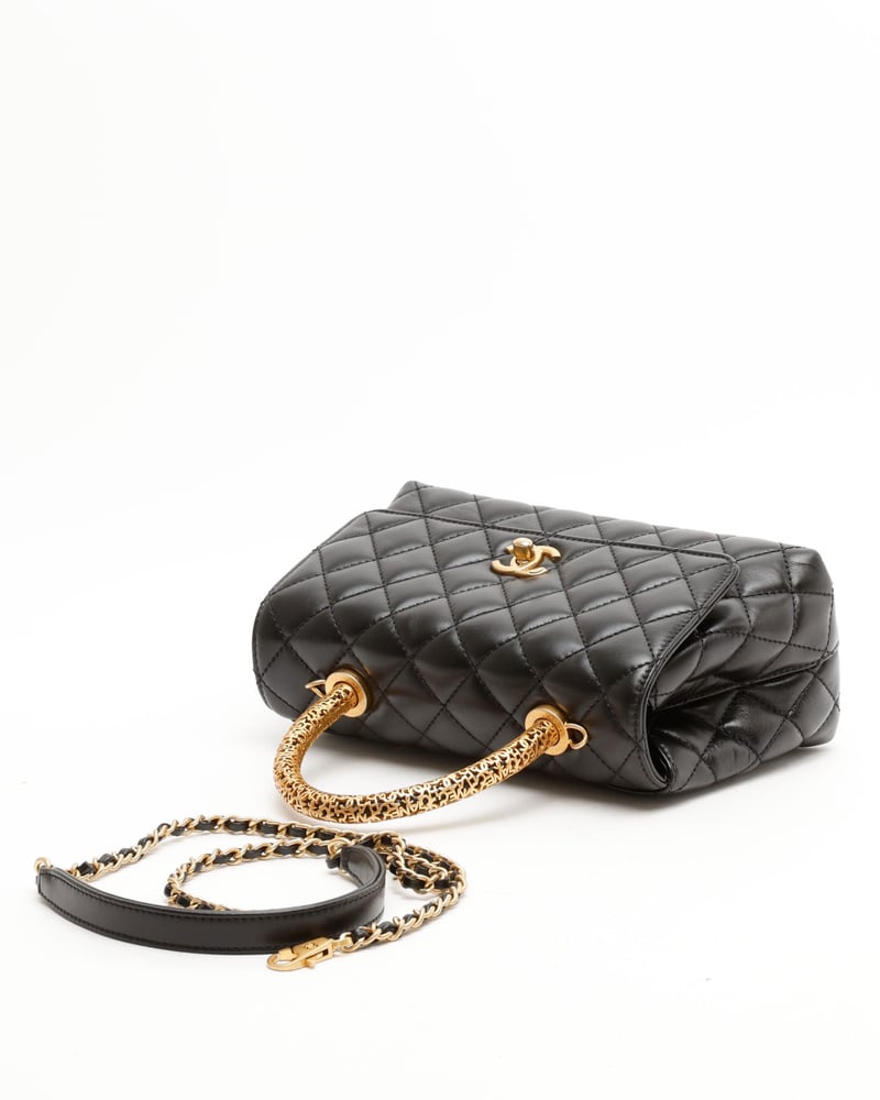 Hohe Ansicht der Chanel Small Coco Handle Tasche aus schwarzem Leder mit ihrem gemusterten, goldfarbenen Tragegriff.