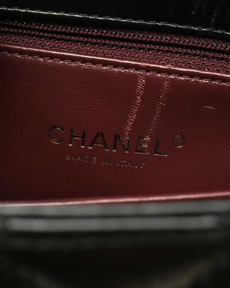 Nahaufnahme des goldenen 'Made in Italy'-Markenstempels im burgunderroten Innenfutter der Chanel Small Coco Handle Tasche.