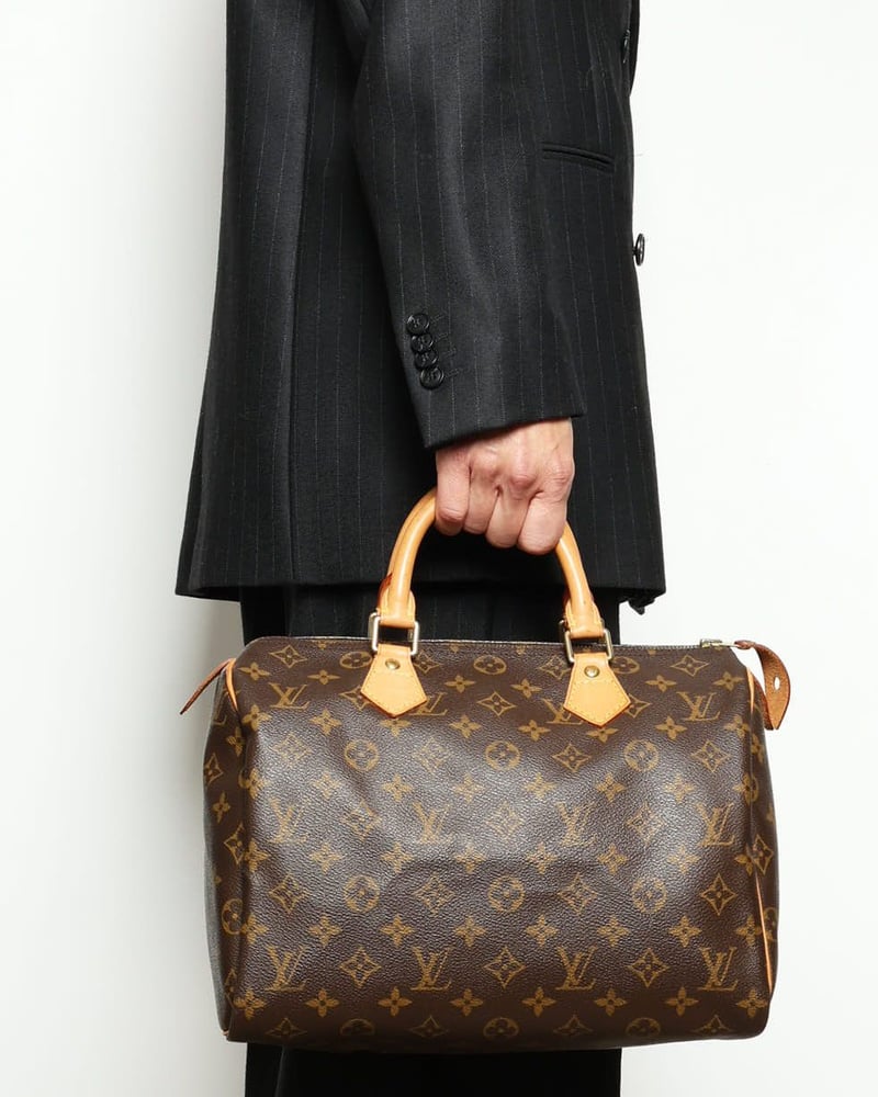 Louis Vuitton Monogram Speedy Bandoulière 30 Taschen aus braunem Canvas mit Vachetta-Ledergriffen vor Nadelstreifenanzug.