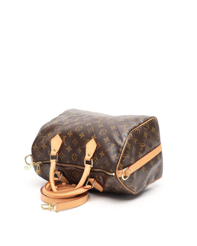 Seitenansicht der liegenden Louis Vuitton Monogram Speedy Bandoulière 35 Taschen mit Vachetta-Lederbesatz auf weißem Grund.