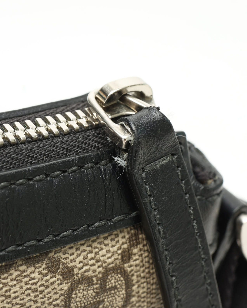 Close-up of the Gucci Messenger Bag's silver zip closure, black leather trim, and GG Supreme canvas.