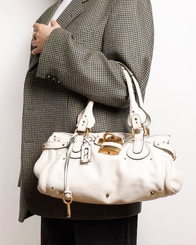 Person in checkered blazer carrying a white Chloé Paddington bag with gold details.
